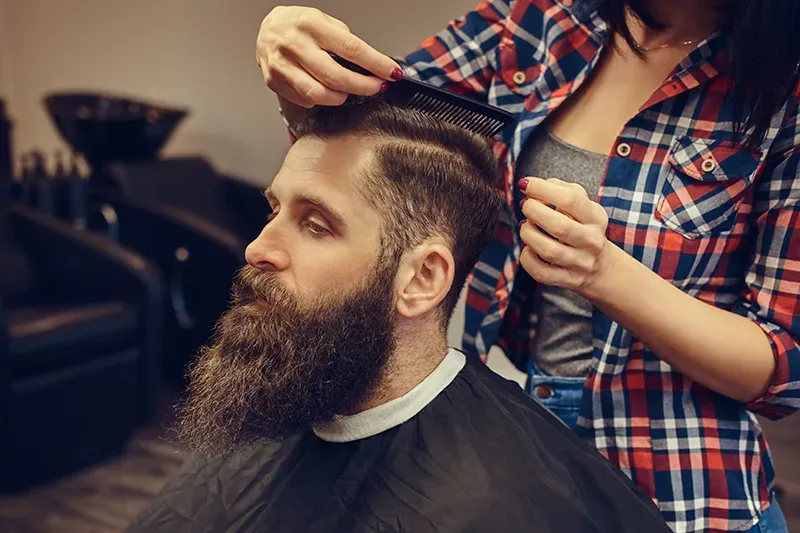 Homme barbu train d'être coiffé